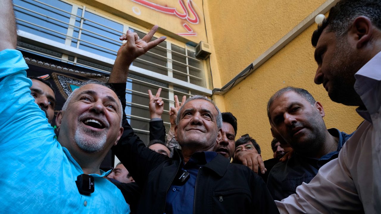 Reformist candidate for the Iran's presidential election Masoud Pezeshkian, center, flashes a victory sign after casting his vote as he is accompanied by former Foreign Minister Mohammad Javad Zarif, left, at a polling station in Shahr-e-Qods near Tehran, Iran, on Friday, July 5, 2024.